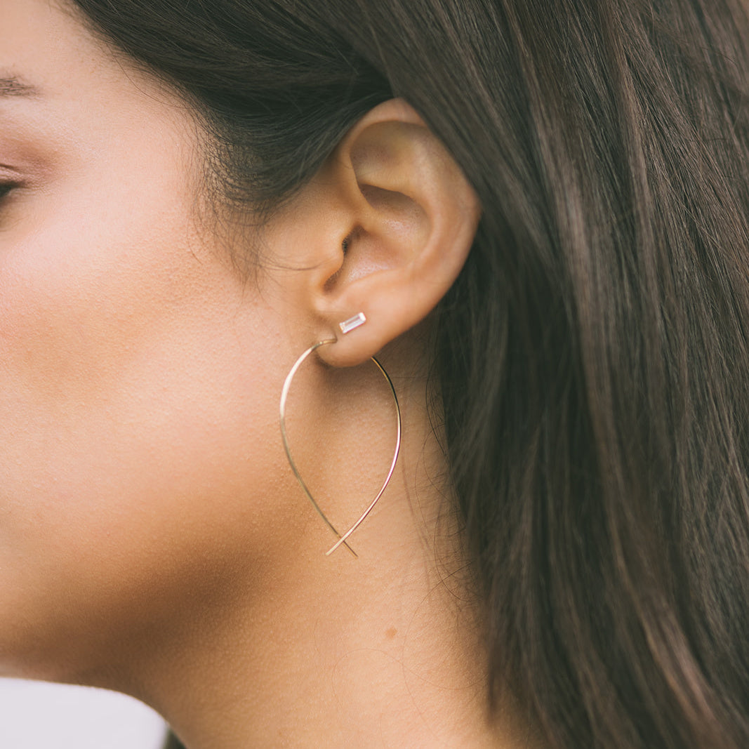 Close-up of a woman wearing elegant handmade earrings Carlsbad with a unique curved design