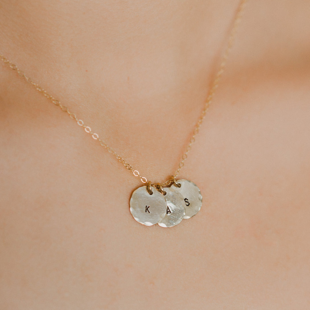 Gold necklace with two round pendants on a person's neck