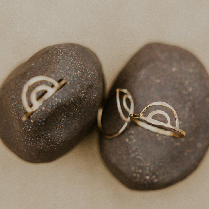3 gold rainbow aloha rings resting on a rock