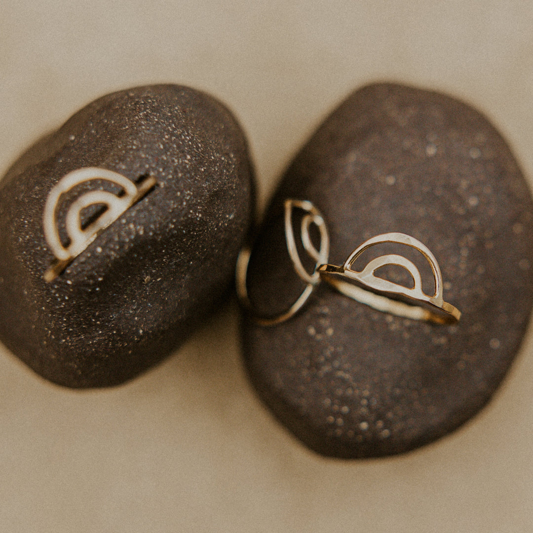 3 rainbow shaped aloha rings resting on a dark rock