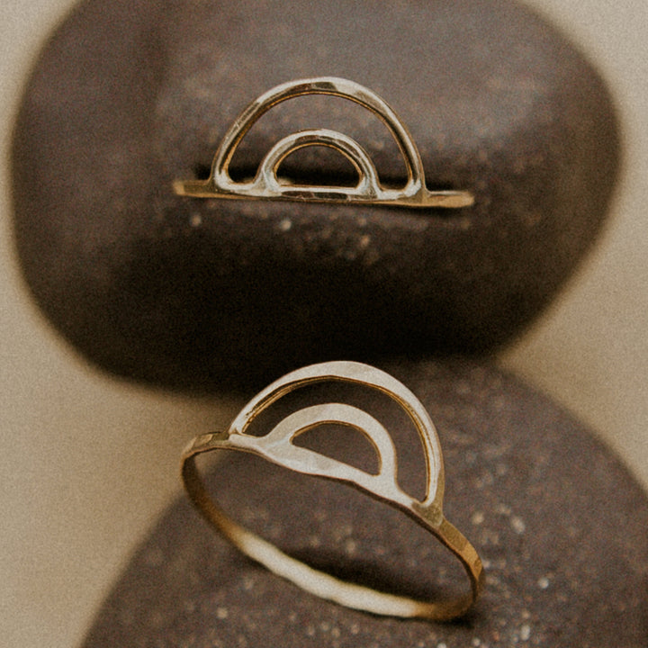 3 rainbow shaped aloha rings sitting on a rock