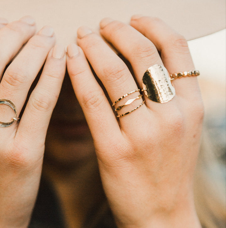 Close-up of hands with 3 gold stacked  rings  on a 
blurred background