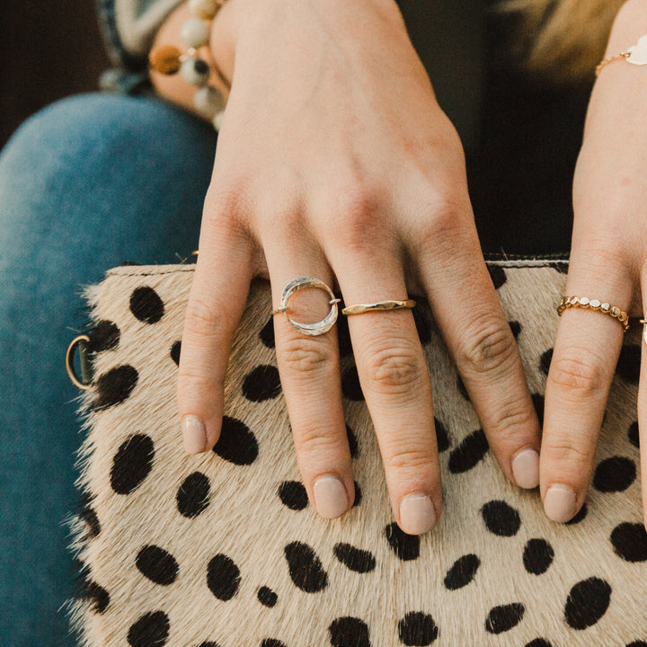 Close-up of hands with gold diamond hammered rings on a leopard print clutch