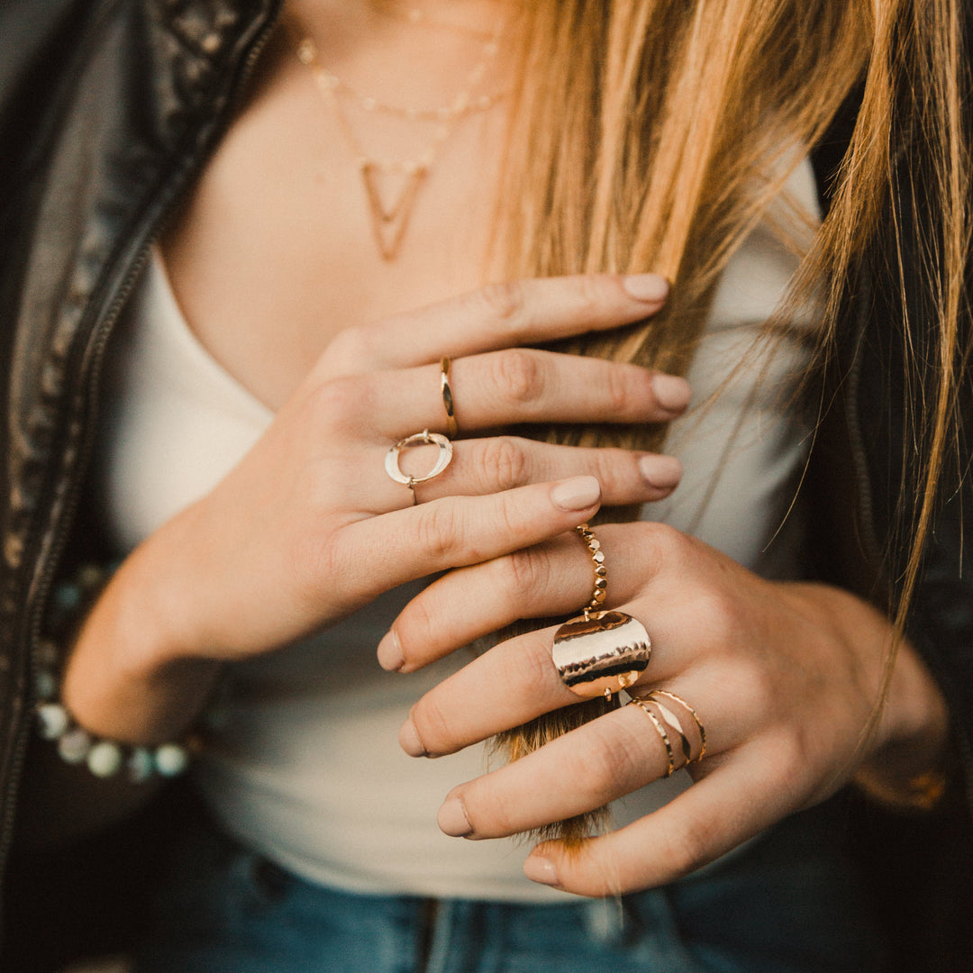 Close-up of a person wearing multiple rings on their fingers.