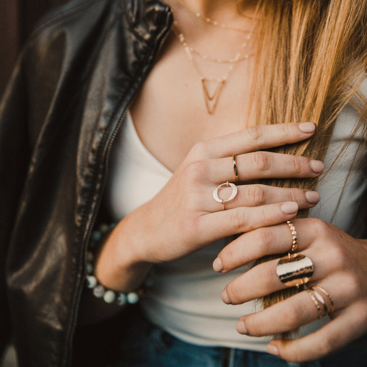 Close-up of a person wearing multiple diamond hammered rings on their fingers, with a focus on jewelry.