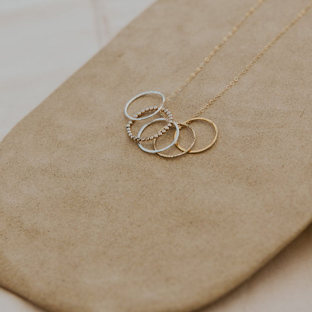 Gold and silver ring necklace on a beige surface