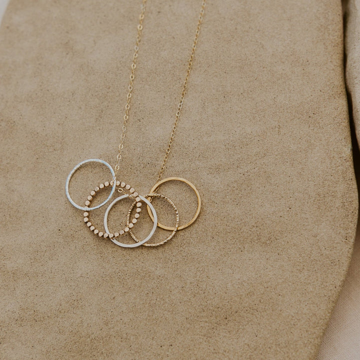 Gold necklace with interlocking rings on a beige surface