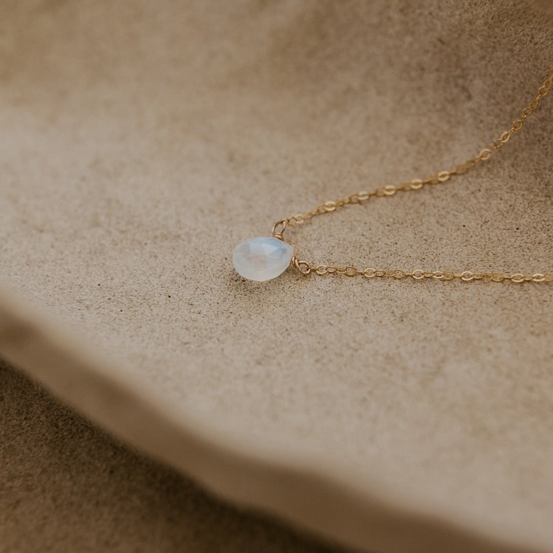 Gold necklace with a pendant on a beige surface