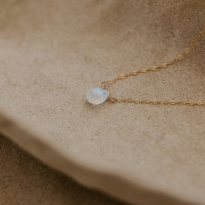 Gold necklace with a pendant on a beige surface