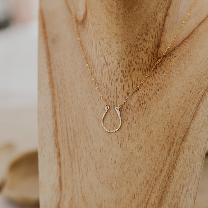 Gold necklace with a horseshoe pendant on a wooden surface