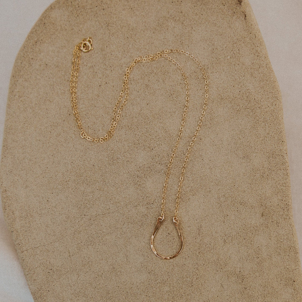 Gold necklace on a textured beige surface
