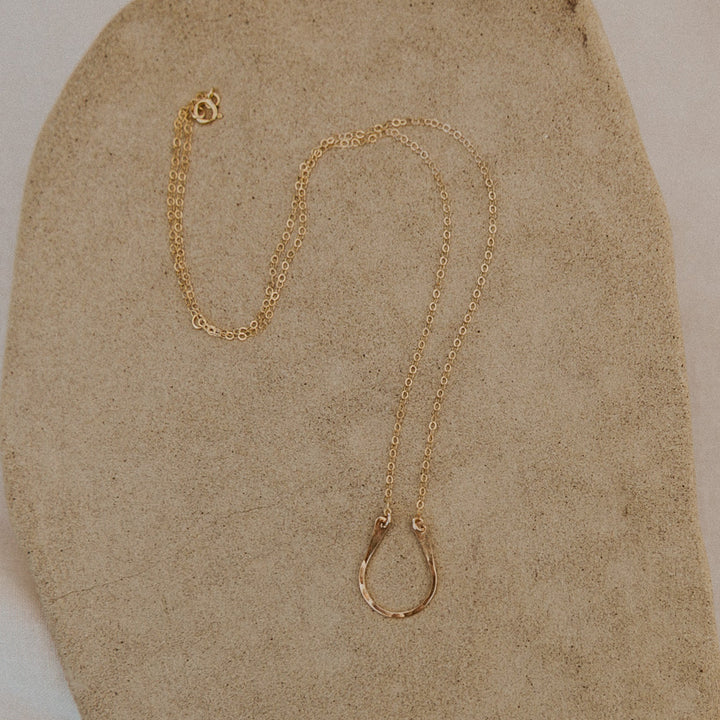 Gold necklace on a textured beige surface