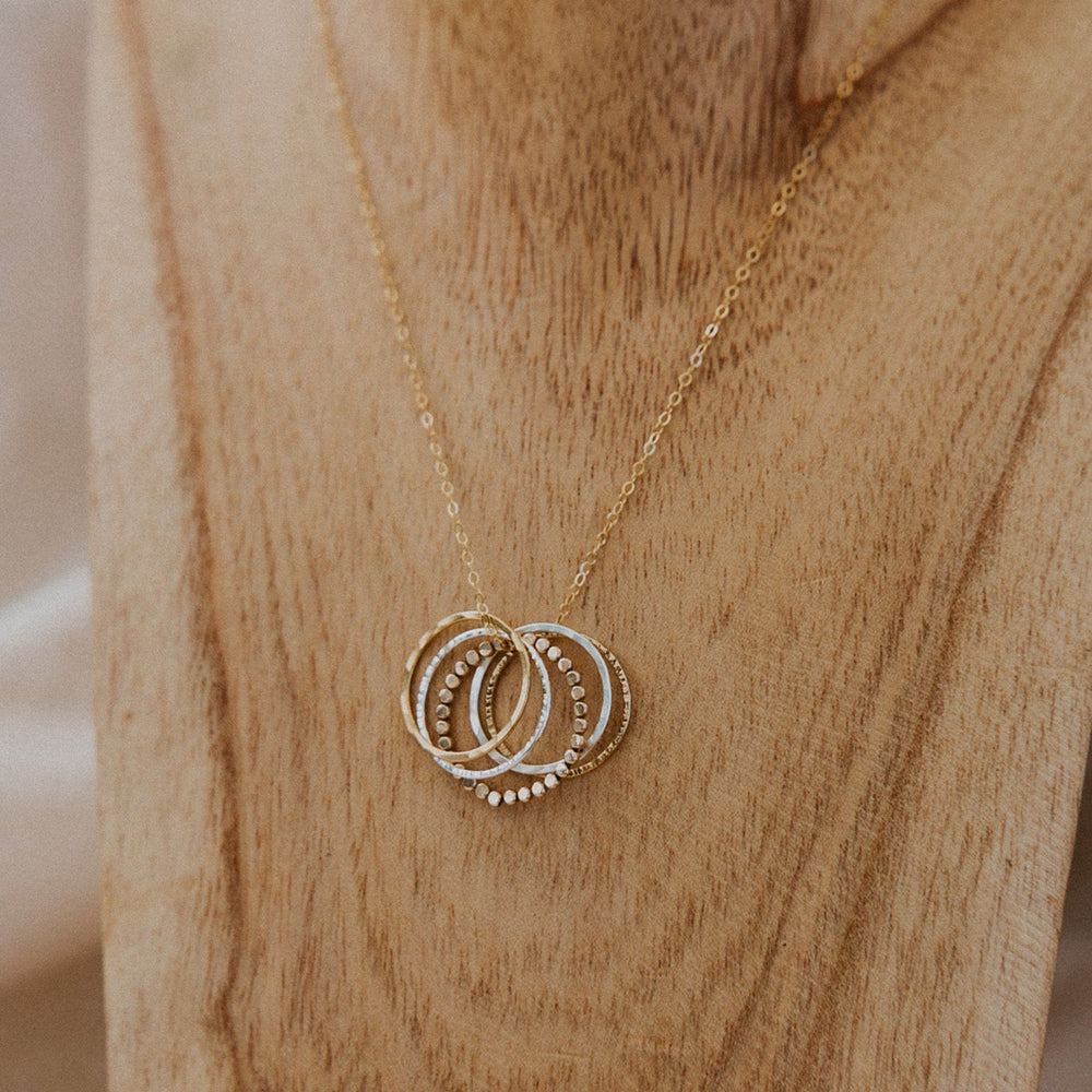 Gold necklace with interlocking rings on a wooden block