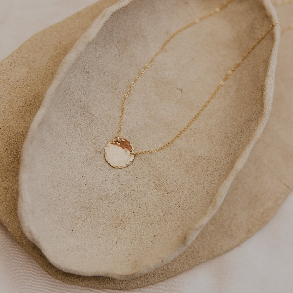 Gold necklace with a pendant on a stone surface