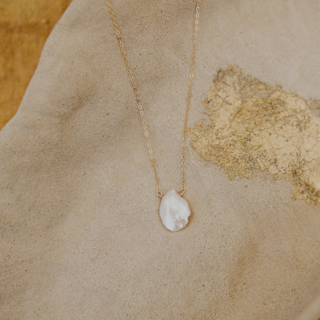 Necklace with a pendant on a textured beige surface
