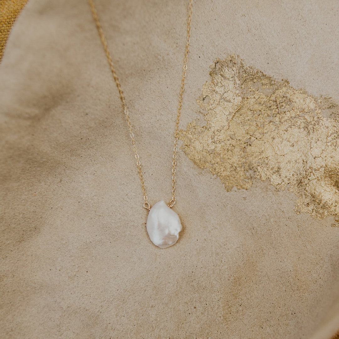 Pearl necklace on a textured beige surface