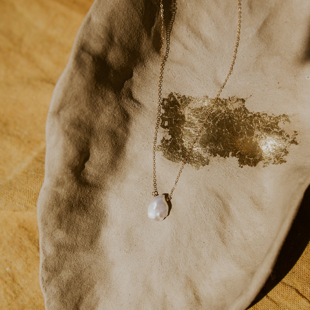 Pearl necklace on a textured beige surface