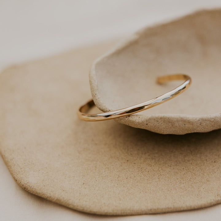Gold bracelet on a textured beige surface