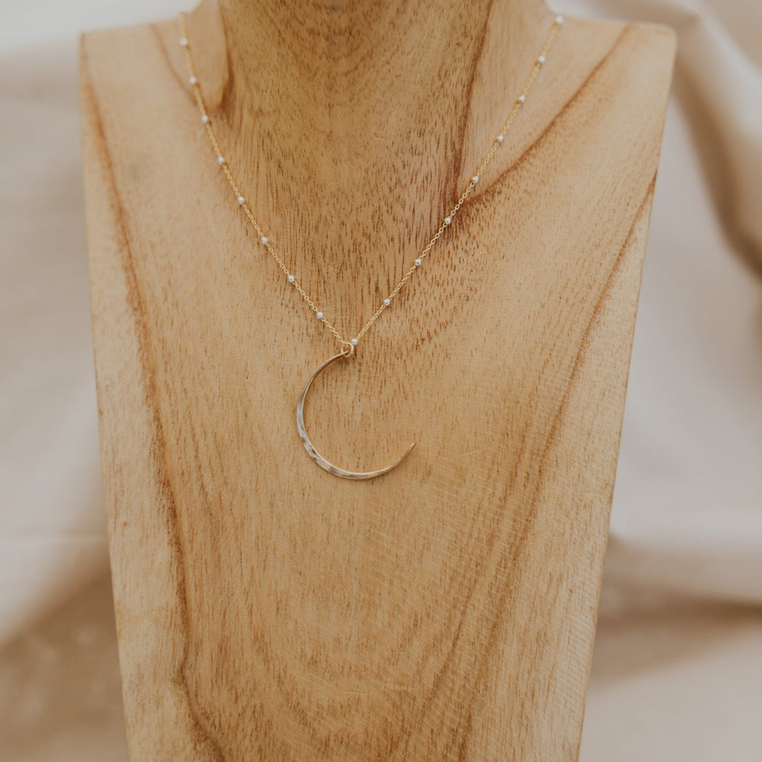 Gold necklace on a wooden bust with a blurred background
