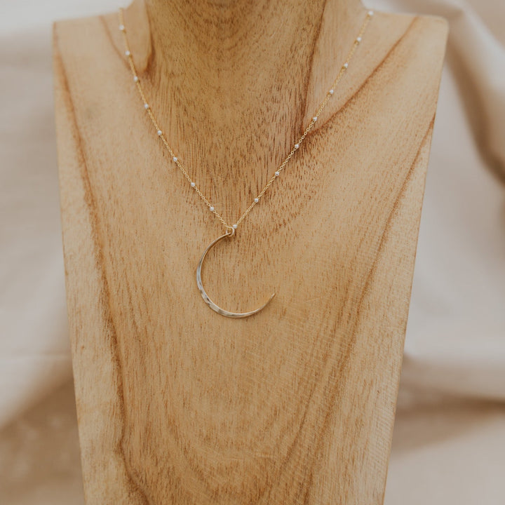 Gold necklace on a wooden bust with a blurred background