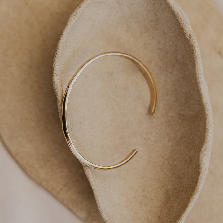 Gold bracelet on a soft beige background