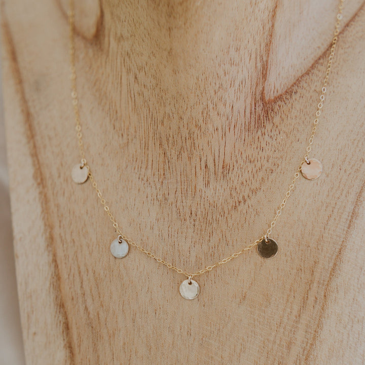 Gold necklace with small round pendants on a wooden surface