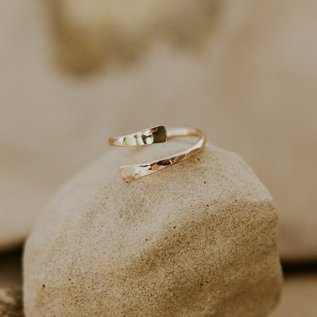 Gold ring on a textured stone surface with a blurred natural background