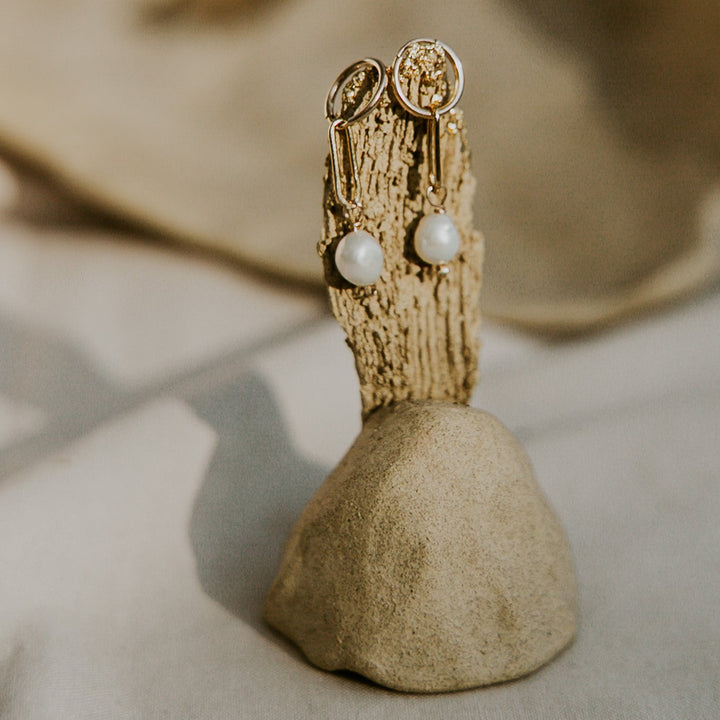 Pair of earrings on a wooden stand with a blurred background
