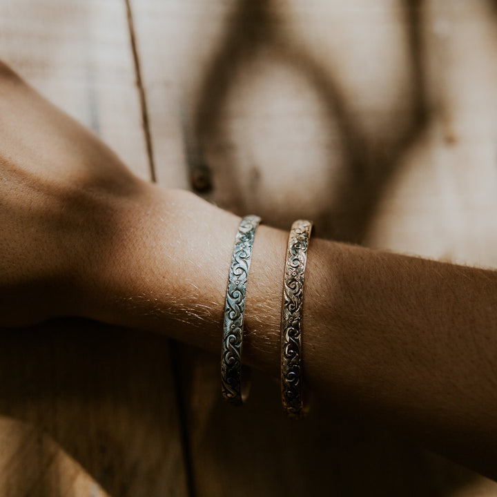 Close-up of a wrist wearing two bracelets on a wooden surface
