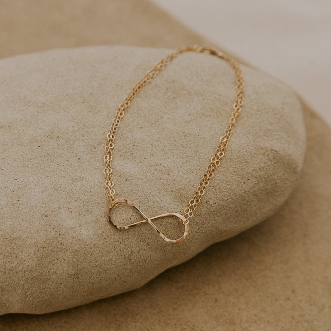 Gold infinity necklace on a stone surface