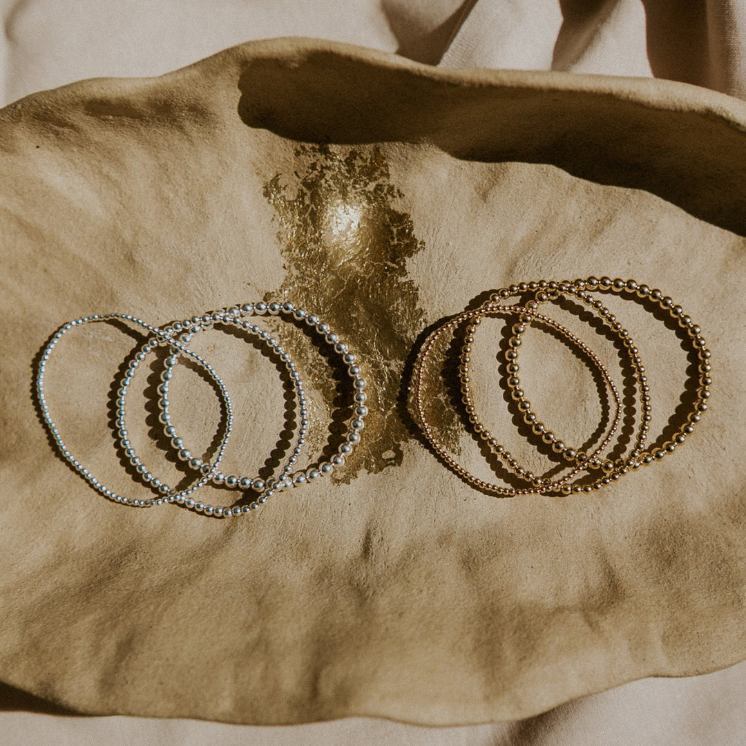 Set of silver and gold bracelets on a textured surface
