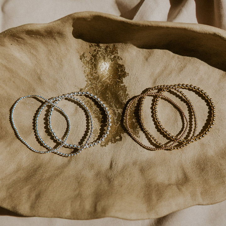 Set of silver and gold bracelets on a textured surface