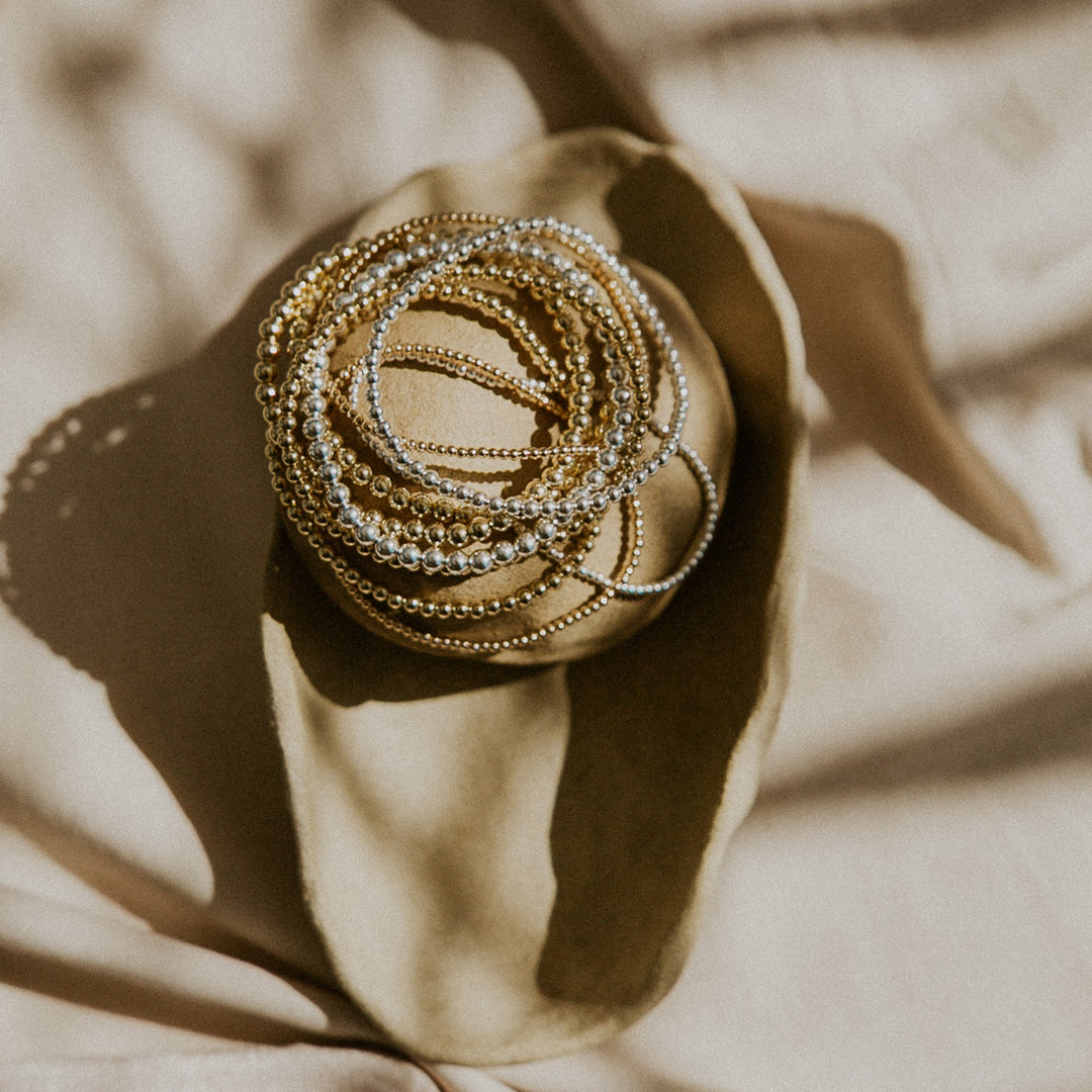 Stack of gold and silver chains on a beige fabric background