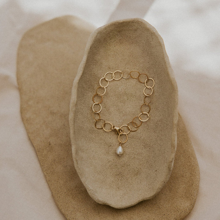 Gold bracelet with a pearl on a stone surface