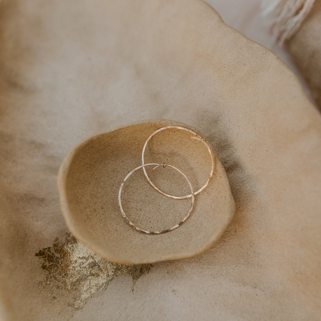 Gold hoop earrings on a textured beige surface