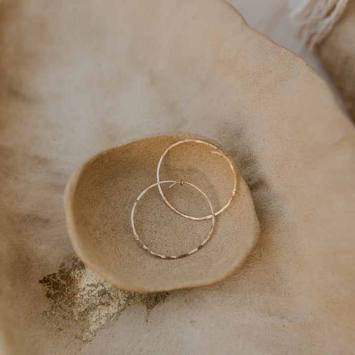 Gold hoop earrings on a textured beige surface