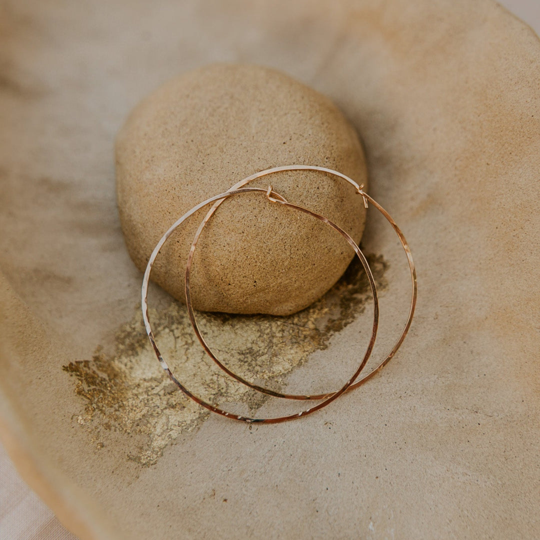 Gold hoop earring on a stone surface