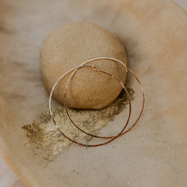 Gold hoop earring on a stone surface