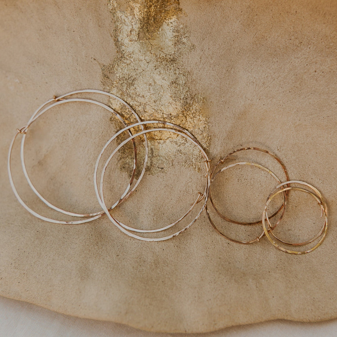 Set of gold hoop earrings on a textured beige surface