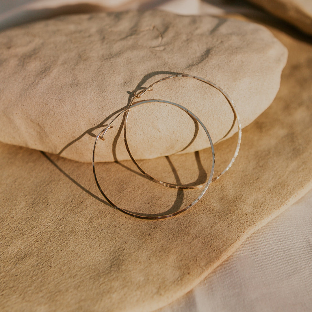 Gold hoop earrings on a textured beige surface