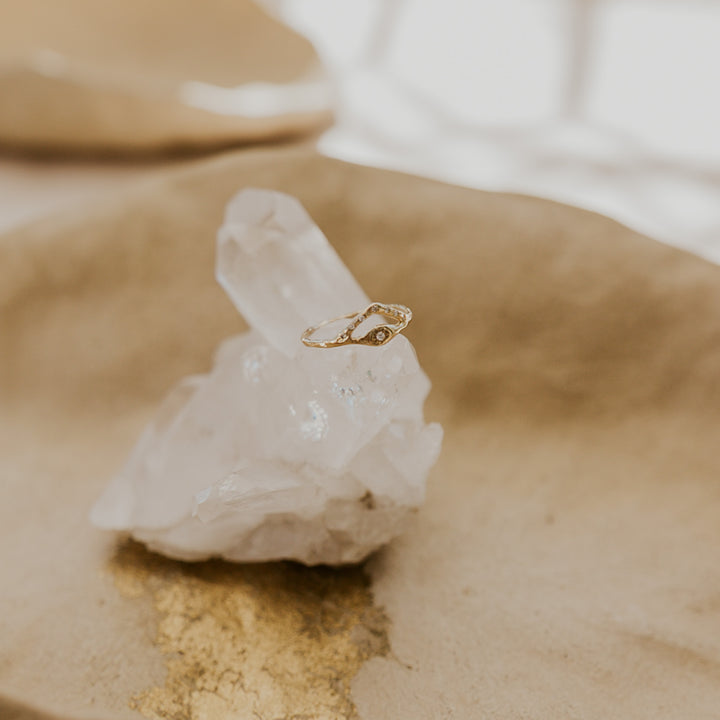 Gold ring on a clear crystal on a beige surface