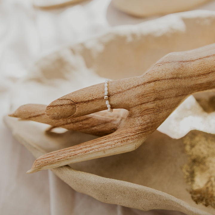 Close-up of a hand holding a ring with a blurred natural background