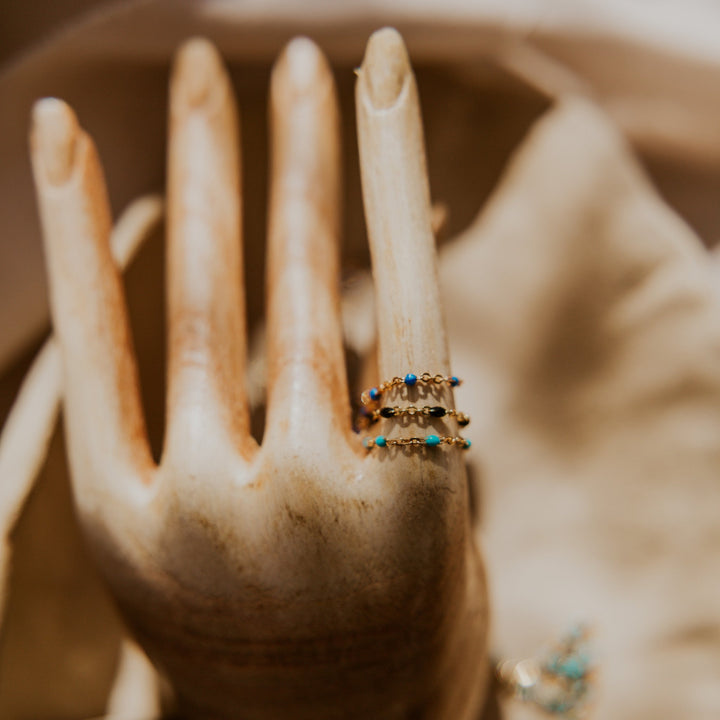 Hand wearing multiple rings with turquoise stones on a blurred background