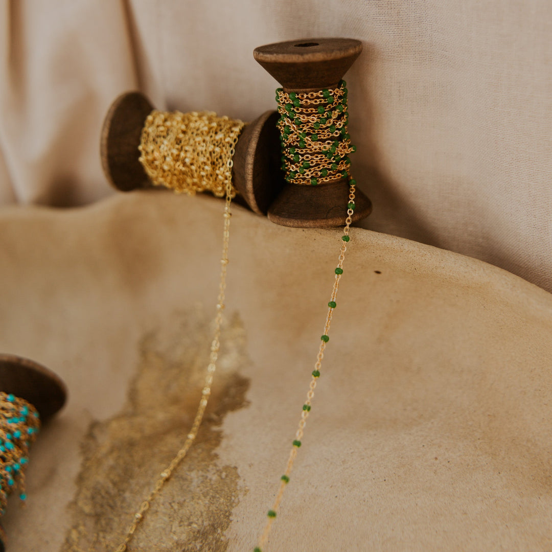 Spools of gold and green chain on a textured surface