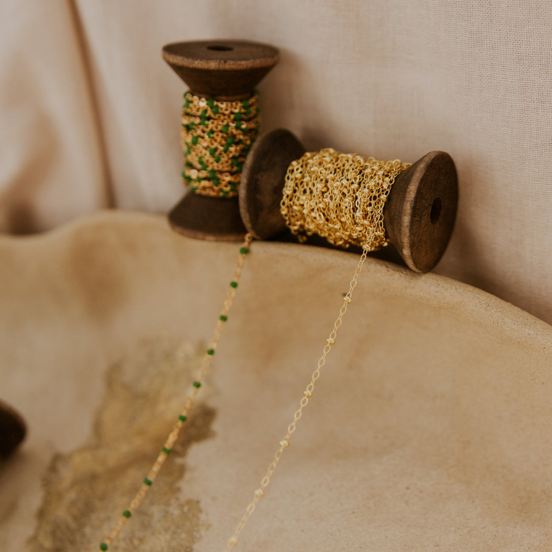 Wooden spools with green and gold thread on a textured surface