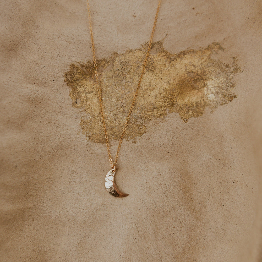 Necklace with a leaf pendant on a textured beige background