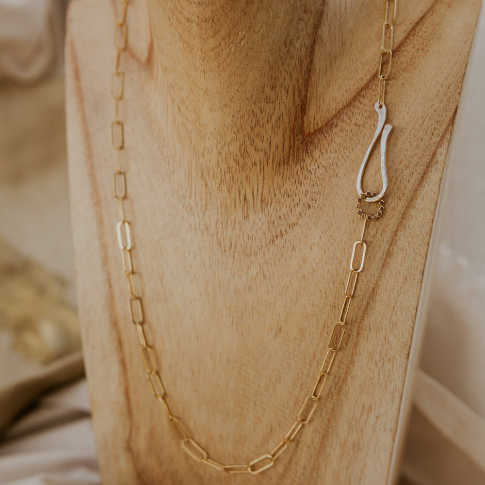 Gold chain necklace with a unique pendant on a wooden surface