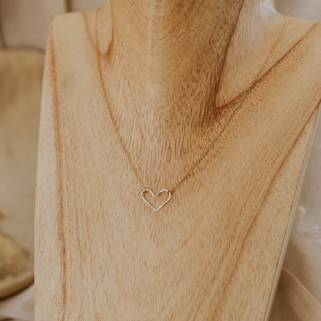 Gold heart-shaped necklace on a wooden stand
