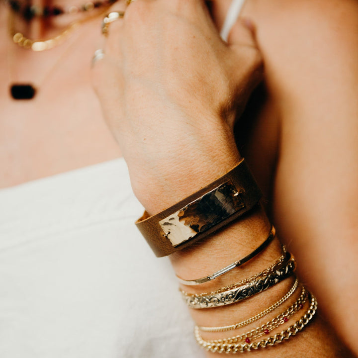 Close-up of a person's wrist wearing multiple bracelets on a blurred background