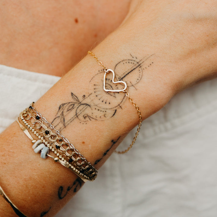Gold bracelets on a wrist with visible tattoos